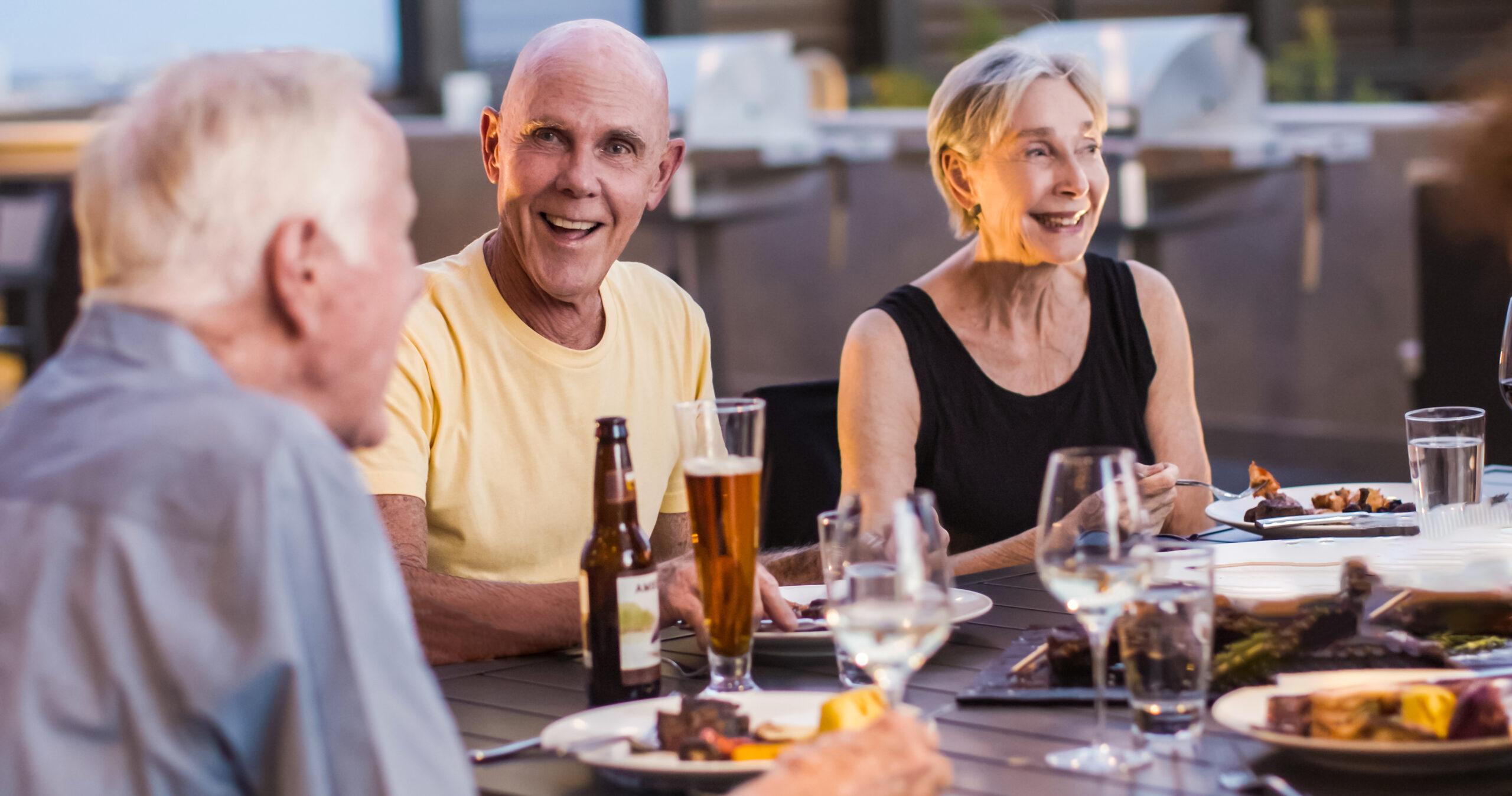 Three people dining and drinking in an outdoor setting.